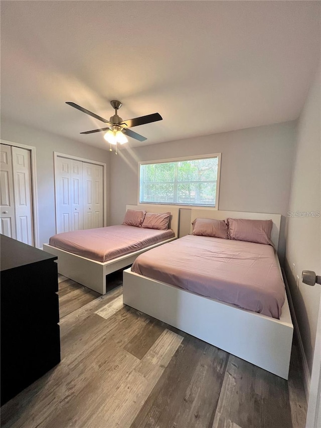 bedroom with ceiling fan, two closets, and light wood-type flooring