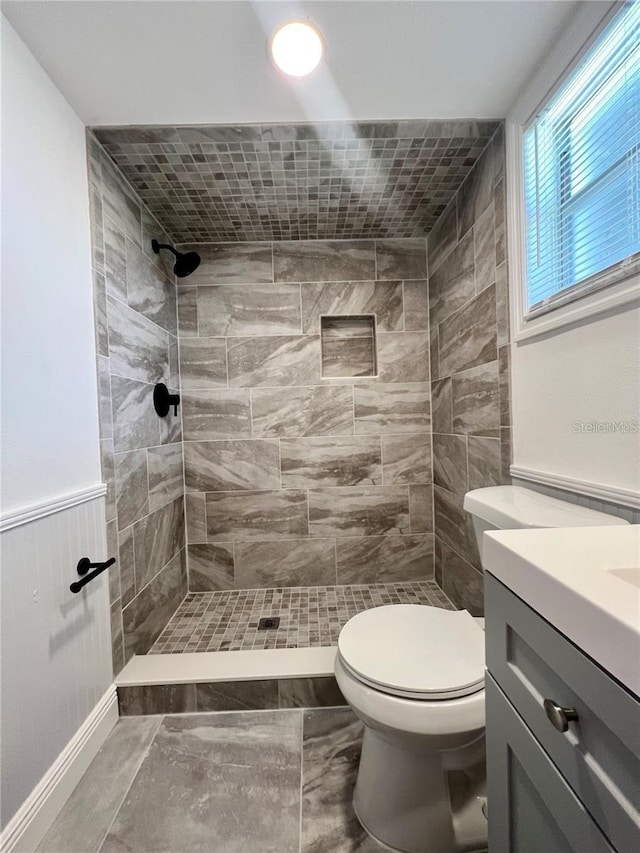 bathroom with vanity, toilet, and a tile shower