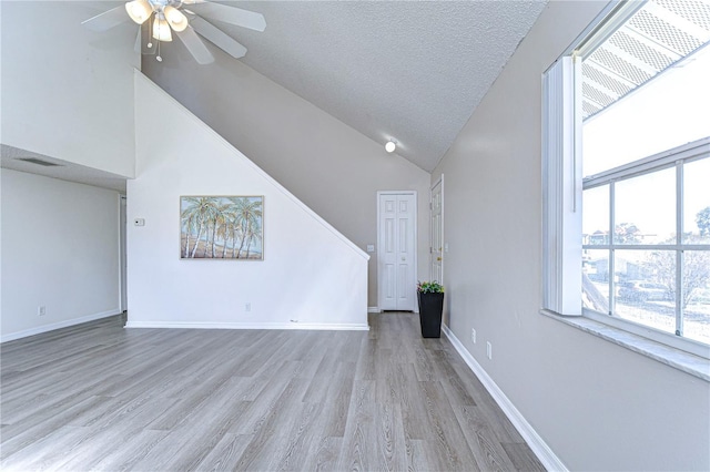 unfurnished living room with ceiling fan, high vaulted ceiling, light hardwood / wood-style flooring, and a textured ceiling