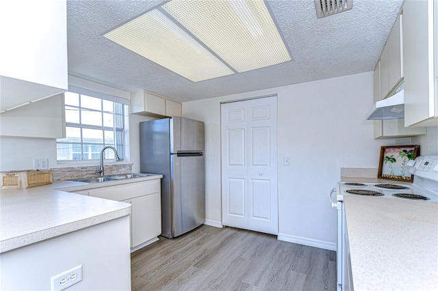 kitchen with sink, stainless steel refrigerator, white range with electric cooktop, light hardwood / wood-style floors, and a textured ceiling