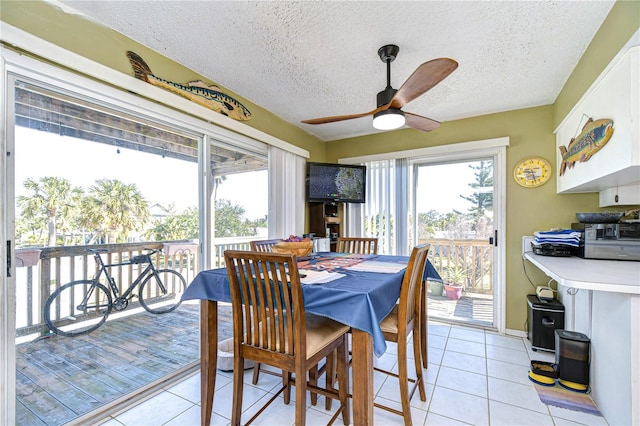 tiled dining space with ceiling fan, plenty of natural light, and a textured ceiling