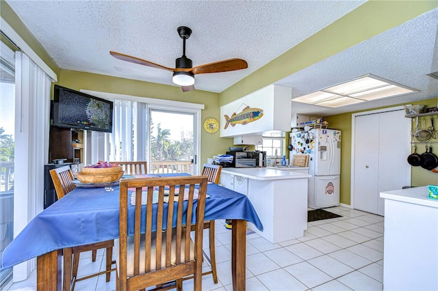 dining space with ceiling fan, light tile patterned floors, and a textured ceiling