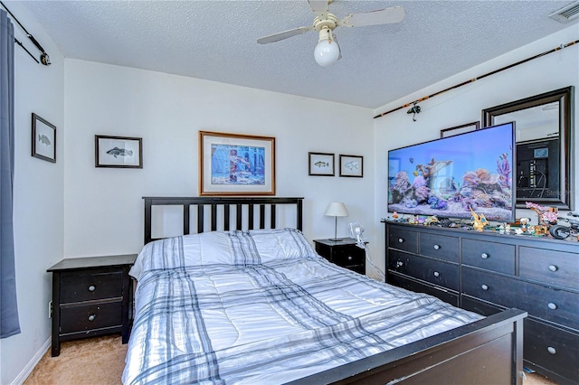 bedroom with ceiling fan, light colored carpet, and a textured ceiling