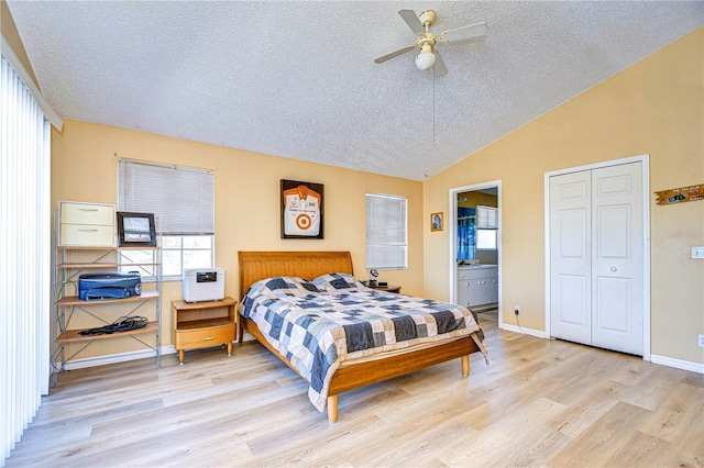 bedroom with vaulted ceiling, ensuite bath, ceiling fan, light hardwood / wood-style floors, and a textured ceiling