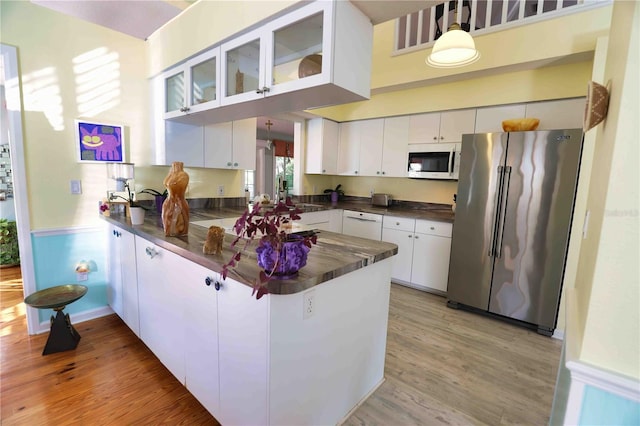 kitchen with white appliances, white cabinetry, hanging light fixtures, kitchen peninsula, and light wood-type flooring