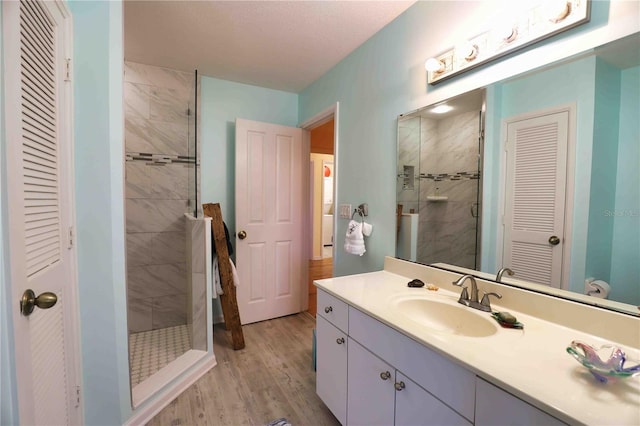 bathroom featuring vanity, a textured ceiling, wood-type flooring, and tiled shower