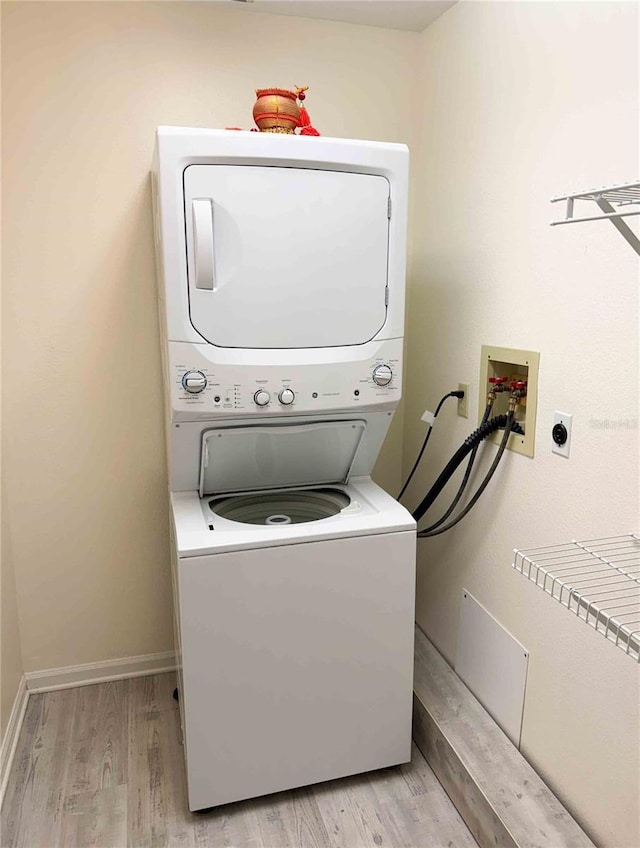 laundry area with light hardwood / wood-style flooring and stacked washing maching and dryer