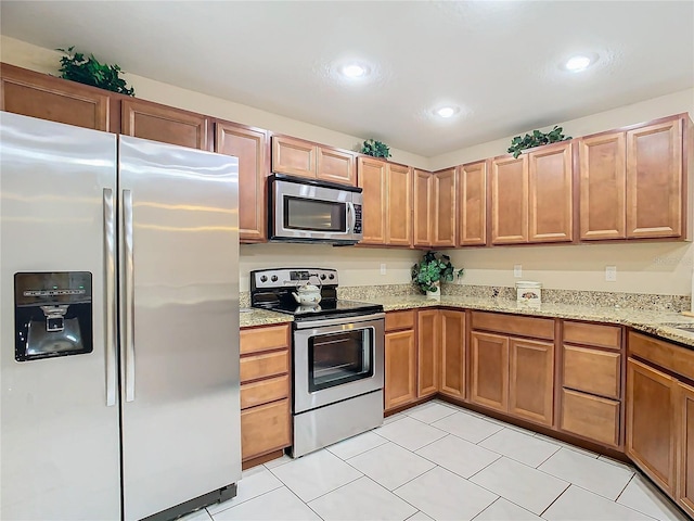 kitchen featuring light stone countertops, appliances with stainless steel finishes, and light tile patterned floors