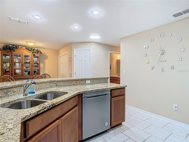 kitchen with light stone countertops, sink, stainless steel dishwasher, and light tile patterned floors