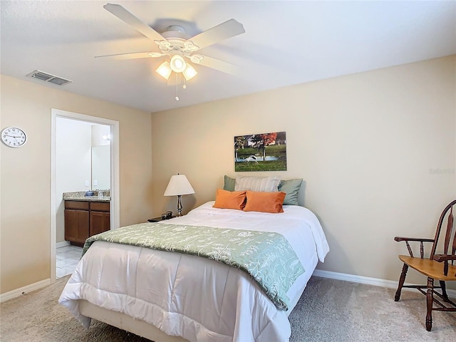 carpeted bedroom with ensuite bathroom and ceiling fan