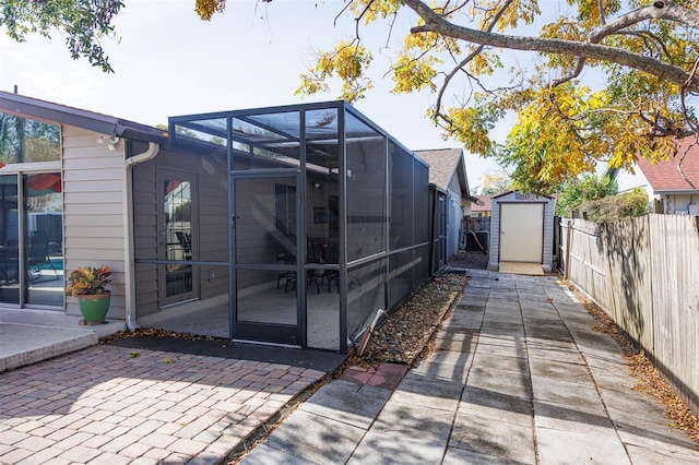 exterior space with a patio, glass enclosure, a fenced backyard, a storage unit, and an outdoor structure