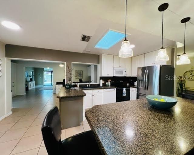 kitchen with a peninsula, white appliances, visible vents, white cabinetry, and pendant lighting