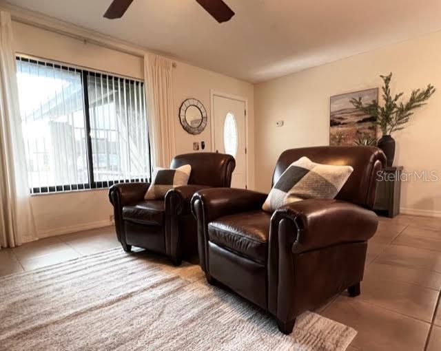 tiled living room featuring a ceiling fan and baseboards