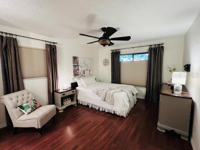 bedroom featuring ceiling fan, a textured ceiling, and wood finished floors