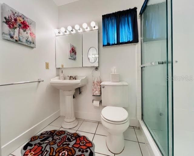 full bathroom with tile patterned flooring, baseboards, a shower with door, and toilet