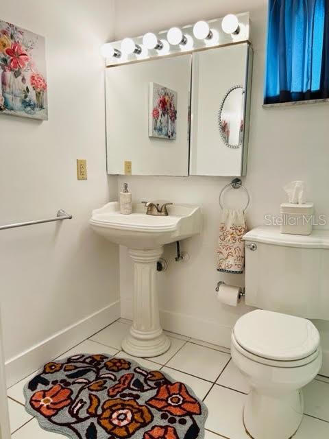 bathroom featuring tile patterned flooring, baseboards, and toilet