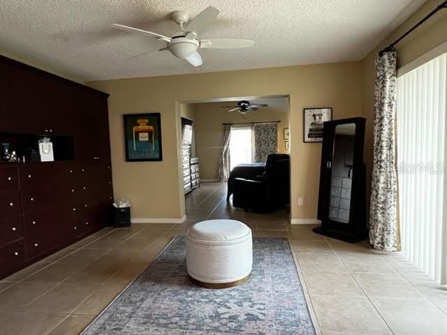 hall with a textured ceiling, light tile patterned flooring, and baseboards