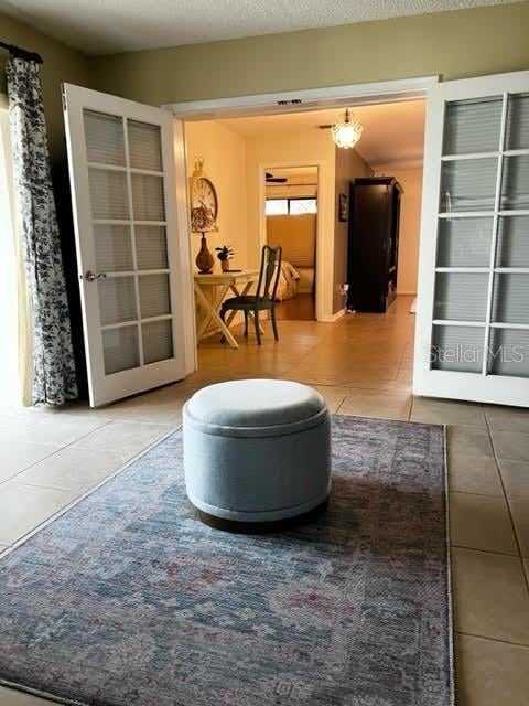 interior space with a textured ceiling, french doors, and tile patterned flooring