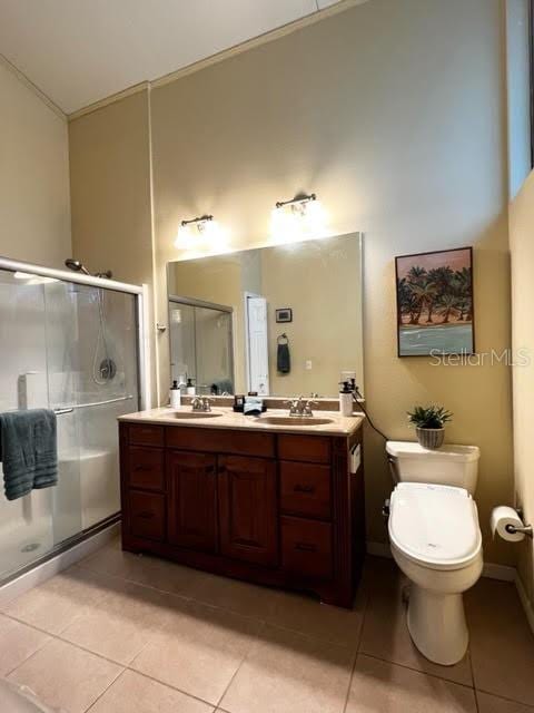 full bathroom featuring a stall shower, double vanity, a sink, and tile patterned floors