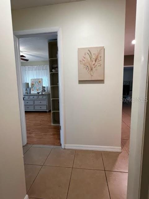 hallway with baseboards and tile patterned floors