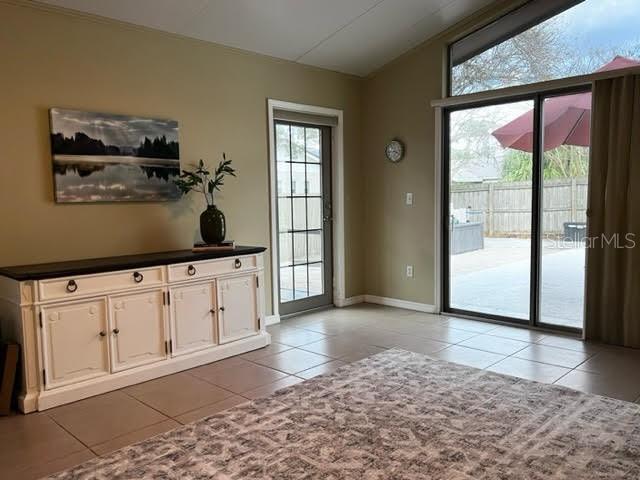 entryway with baseboards, vaulted ceiling, a wealth of natural light, and light tile patterned flooring