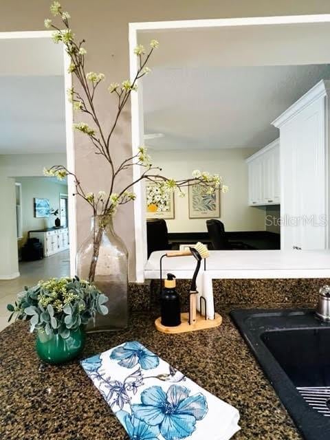 kitchen with dark countertops, a sink, and white cabinetry