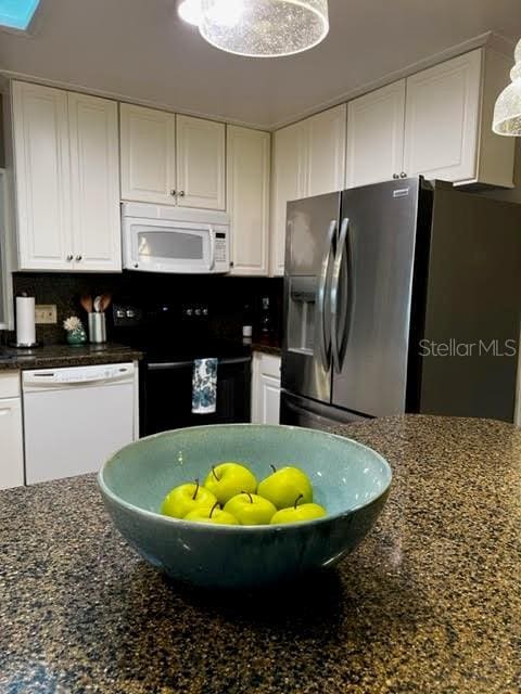 kitchen featuring dark stone counters, white appliances, decorative backsplash, and white cabinets