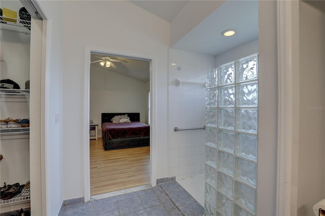 bathroom with tile patterned flooring, vaulted ceiling, and a tile shower