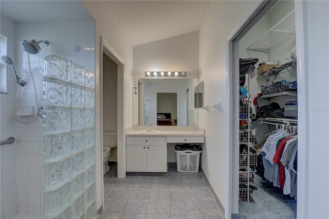 bathroom featuring a tile shower, vanity, vaulted ceiling, and toilet