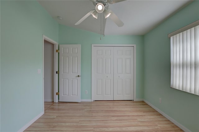 unfurnished bedroom with vaulted ceiling, a closet, ceiling fan, and light wood-type flooring