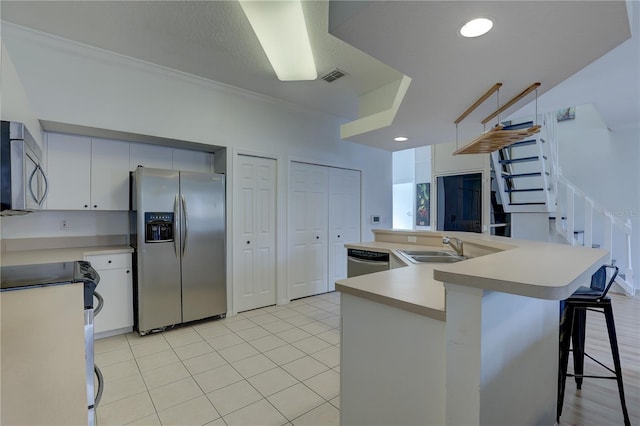 kitchen featuring appliances with stainless steel finishes, sink, white cabinets, a kitchen breakfast bar, and light tile patterned floors