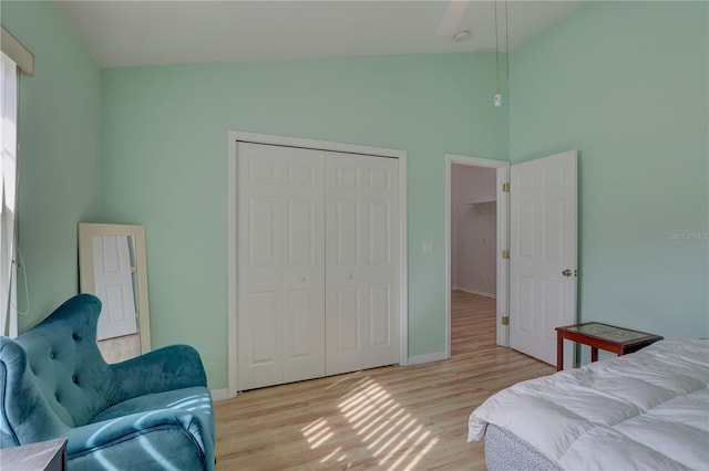 bedroom with vaulted ceiling, light hardwood / wood-style floors, and a closet