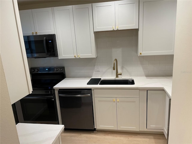 kitchen with dishwashing machine, sink, electric range, and white cabinets