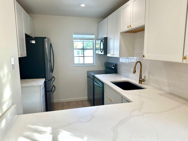 kitchen featuring sink, decorative backsplash, black appliances, and white cabinets