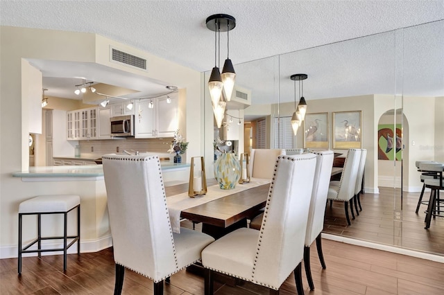 dining area with hardwood / wood-style floors and a textured ceiling