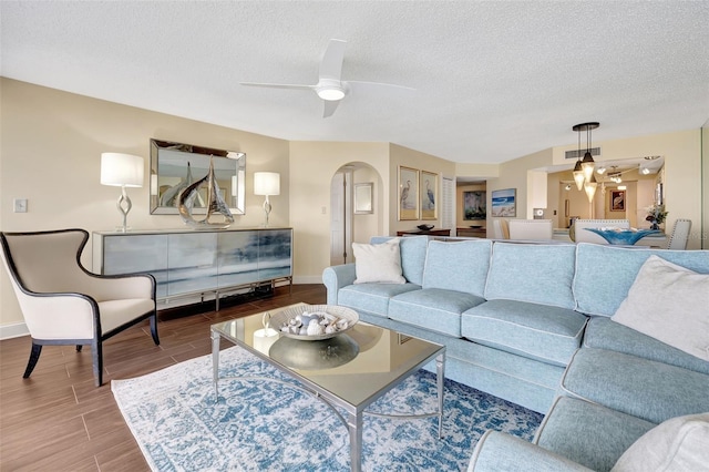 living room with ceiling fan and a textured ceiling