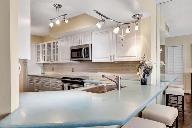 kitchen featuring a kitchen bar, sink, white cabinetry, kitchen peninsula, and stainless steel appliances