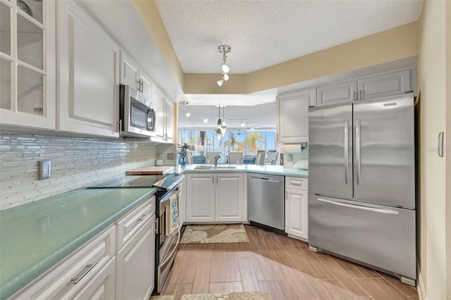 kitchen with sink, hanging light fixtures, stainless steel appliances, decorative backsplash, and white cabinets