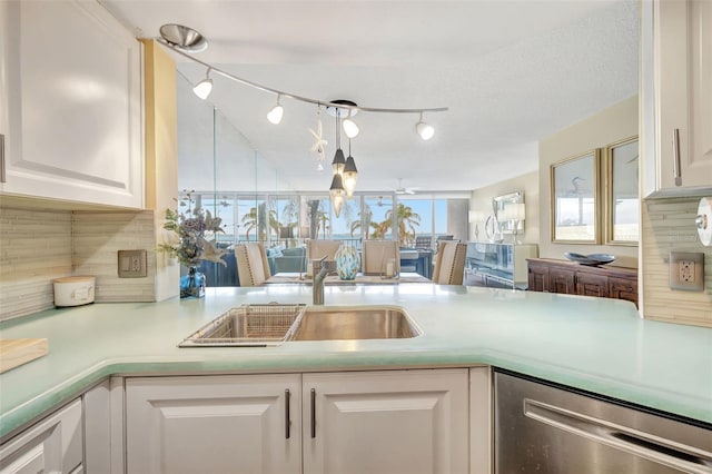 kitchen with white cabinetry, dishwasher, kitchen peninsula, and backsplash