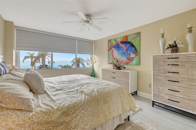 bedroom with ceiling fan, a textured ceiling, and light hardwood / wood-style flooring