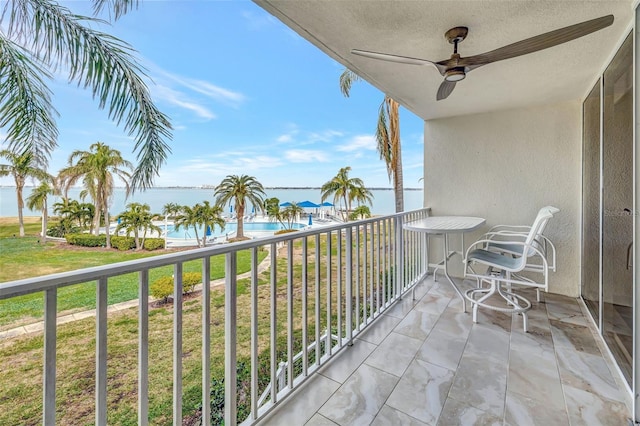 balcony featuring a water view and ceiling fan