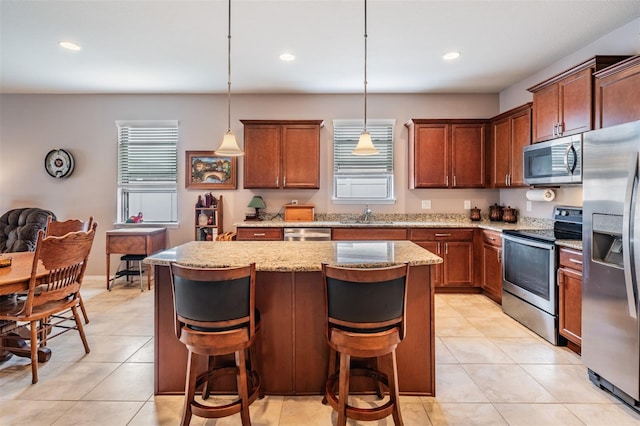 kitchen with pendant lighting, light tile patterned floors, a breakfast bar, appliances with stainless steel finishes, and light stone counters