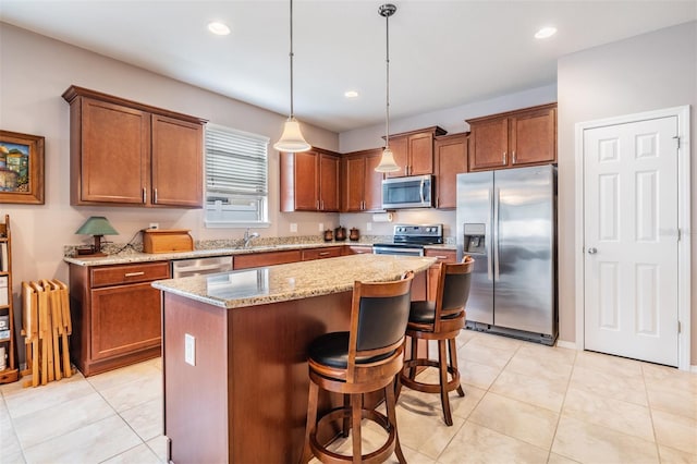 kitchen featuring light stone counters, a center island, hanging light fixtures, stainless steel appliances, and recessed lighting