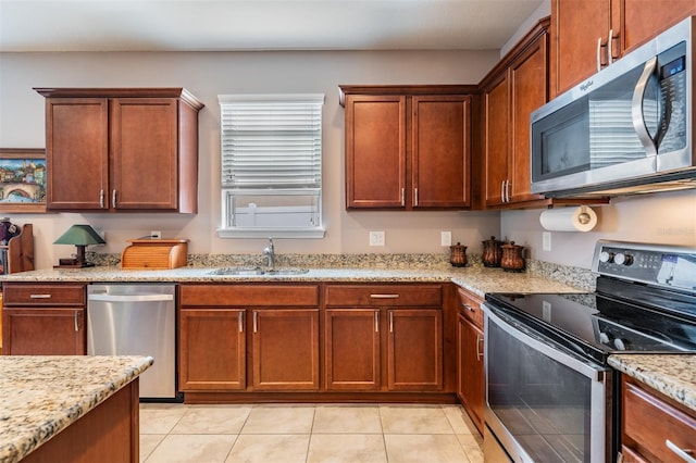 kitchen with light stone countertops, appliances with stainless steel finishes, sink, and light tile patterned floors