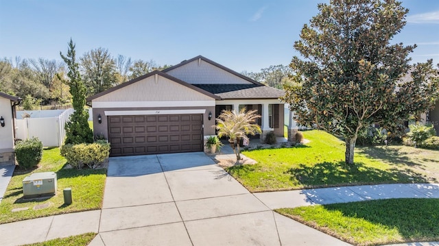 view of front of home featuring a front yard, concrete driveway, fence, and an attached garage