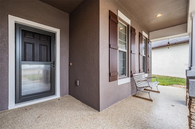 doorway to property featuring a porch and stucco siding