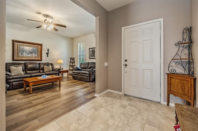 entryway with light wood finished floors, ceiling fan, and baseboards