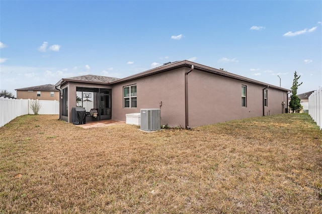 back of house featuring a lawn, stucco siding, a fenced backyard, and central air condition unit