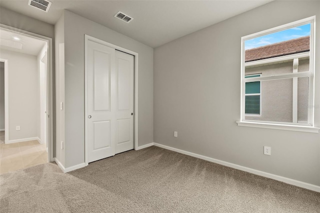 unfurnished bedroom with light colored carpet and a closet