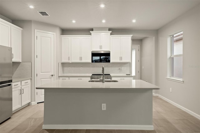 kitchen with stainless steel refrigerator, sink, a kitchen island with sink, and white cabinets